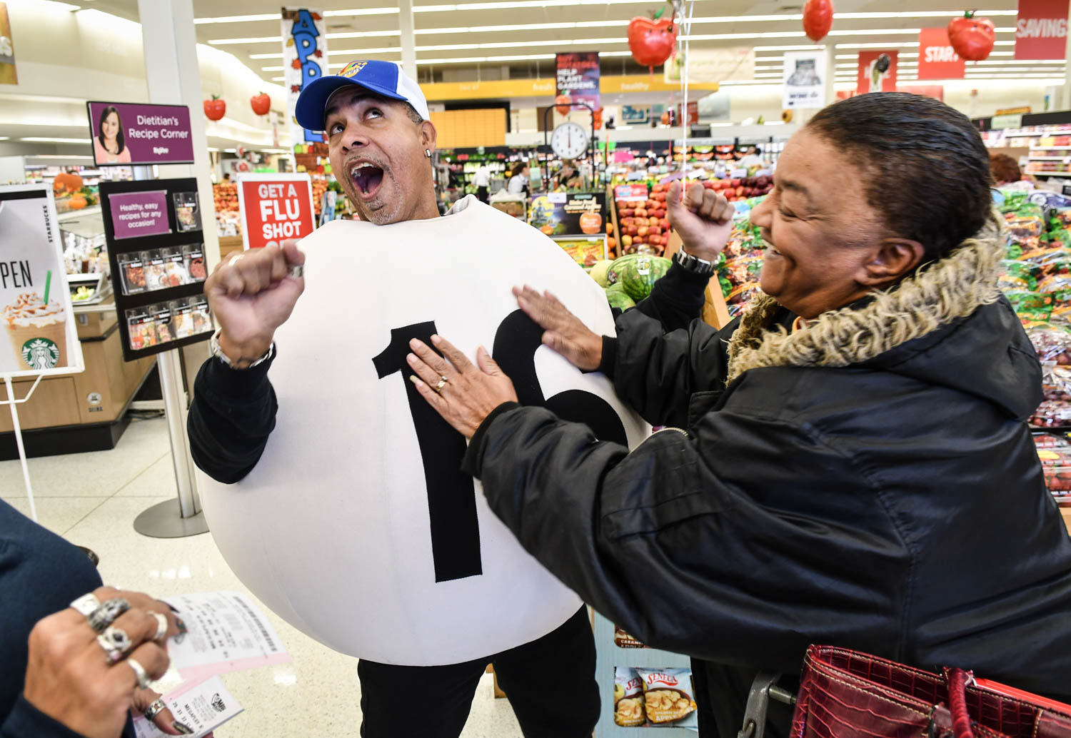 Kathy Clark, of Rock Island, rubs the "Lucky Number 16" costume, worn by Illinois Lottery ambassador Jose Cintron, Thursday, Oct. 18, 2018, at the HyVee grocery store in Milan. Lottery ambassadors gave away 970 free Mega Millions tickets Thursday. Approximately 80 to 100 people were lined up when the ticket giveaway started at 10 am.  (Todd Mizener - Dispatch/Argus) 
