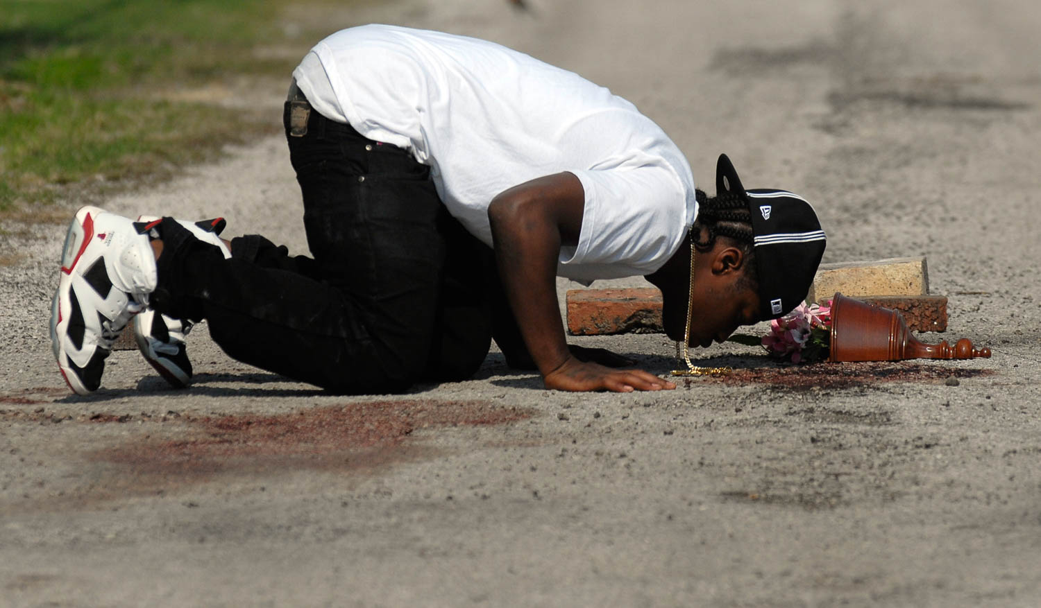 Joe Williams of Carbon Cliff kisses the blood-stained pavement Thursday morning in the East Moline Ill. alley where his cousin Kelton Trice was shot and killed by police Wednesday evening. Police investigators said Trice was killed during an exchange of gunfire with East Moline police officer Sgt. Tom Peterson. (Todd Mizener - Dispatch/Argus)