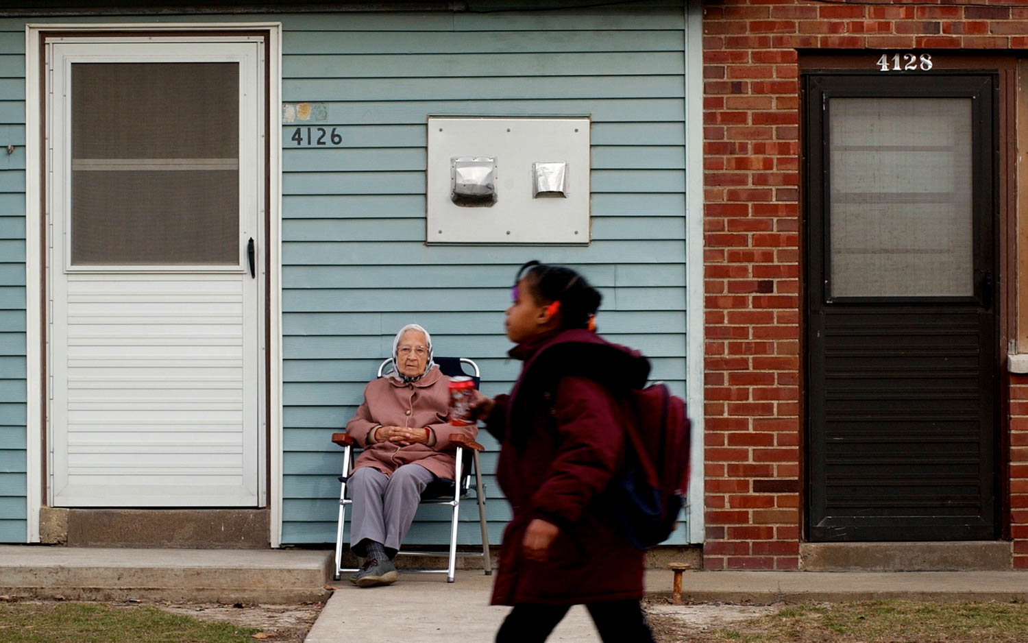 90-year-old Esther Funk of Moline watches the children come home from school Wednesday afternoon while she sitting outside her apartment in Springbrook Courts. Funk has lived in the public housing complex for 50-years. When the weather is nice she says she can usually be found outside enjoying the view from her front stoop. (Todd Mizener - Dispatch/Argus)