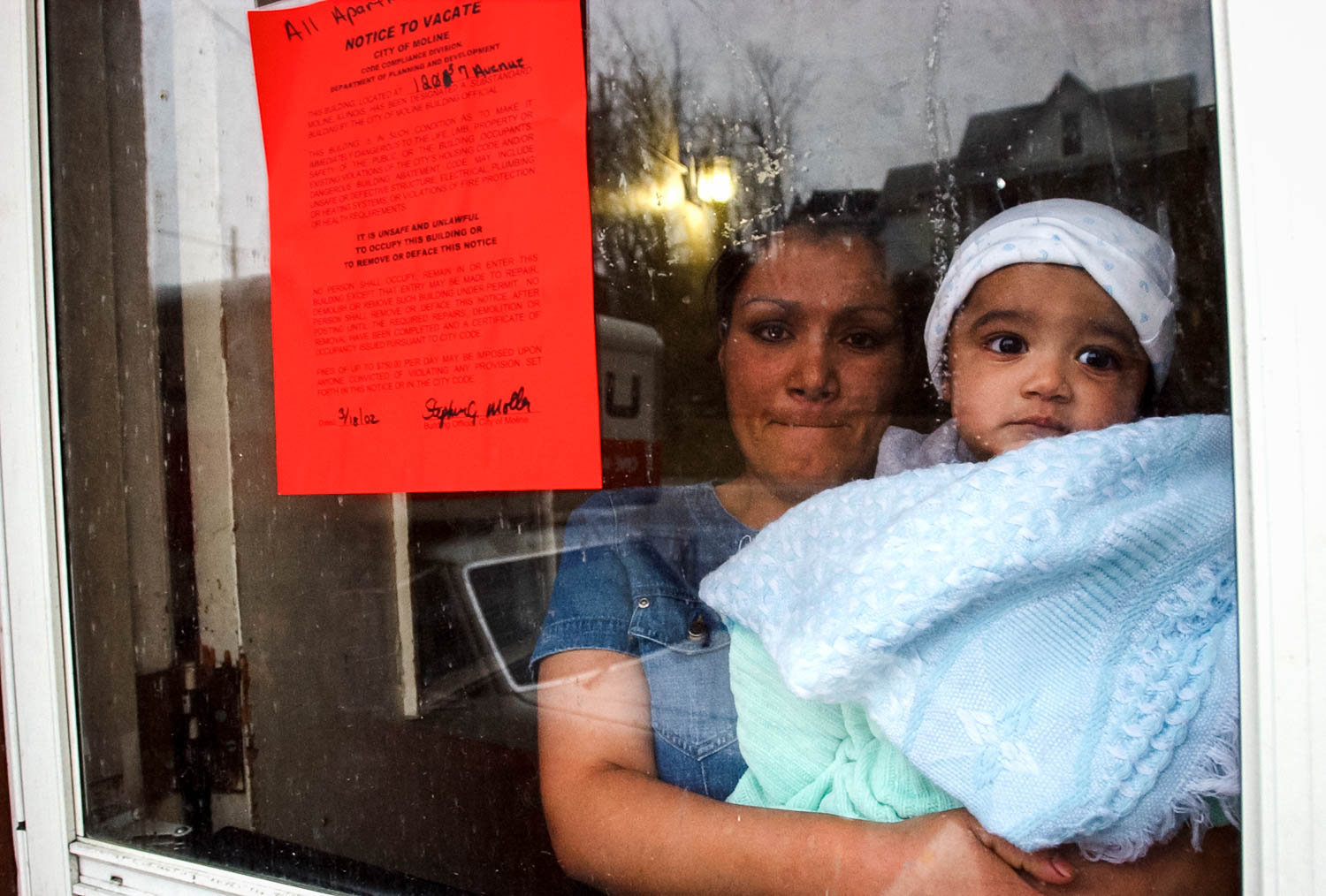 Luzmaria Carpia and her 7-month son Alejandero watch their friends and neighbors load their belongings into trucks and cars after the city of Moline evicted the apartment building's 10 families because safety violations. The families had less than one day of notice to move out. The mother of five children, whose husband is back in Mexico, didn't have any idea where she planned to go. (Todd Mizener - Dispatch/Argus)