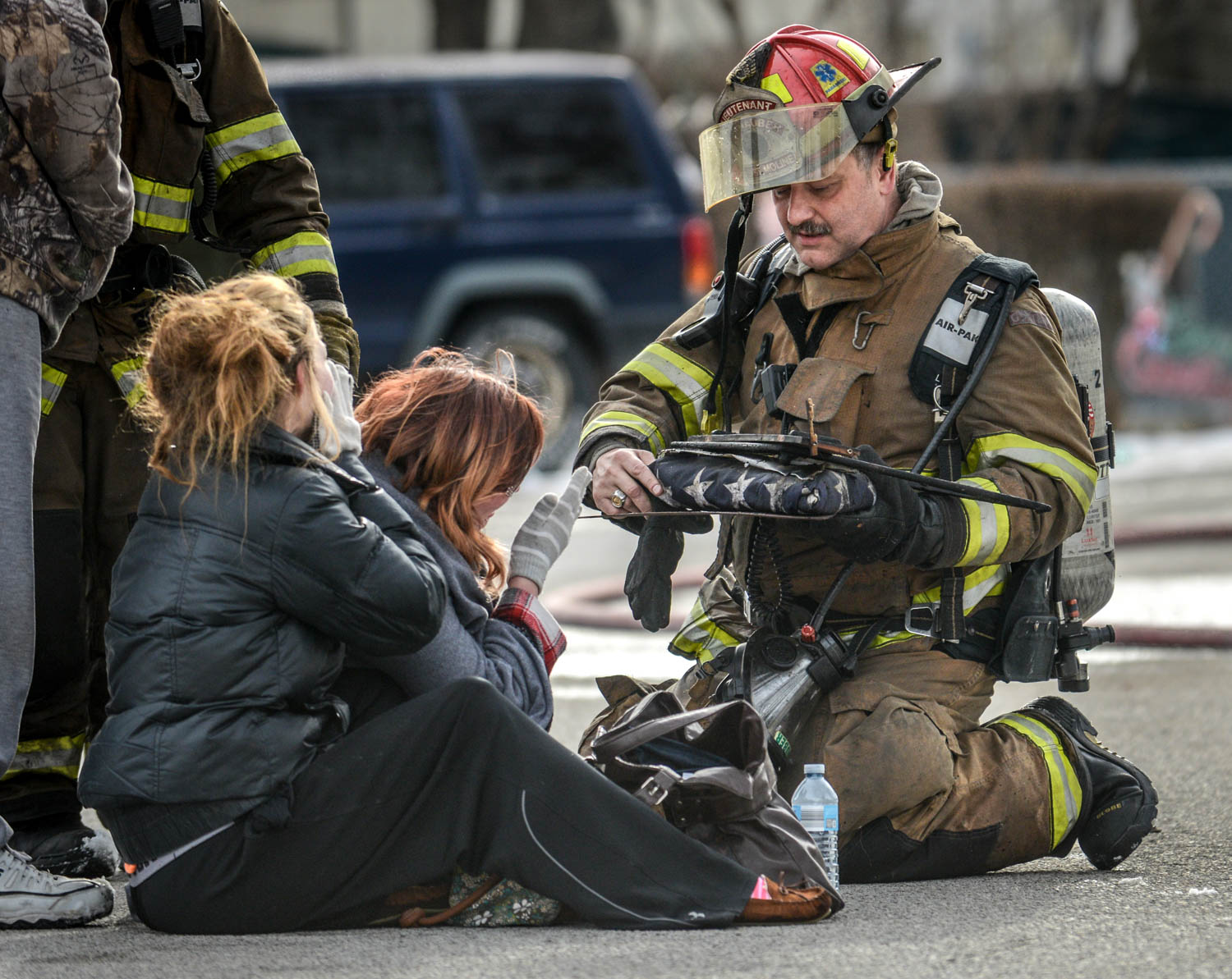 East Moline Fire Lt. Scott Schnauber presents Emily Whipple, center, and her sister Amanda Hocker, with a folded American flag he rescued from the fire that destroyed Ms. Whipple’s mobile home Friday in East Moline. The flag had adorned the coffin of her grandfather and Navy veteran, Paul Sinksen. Lt. Schnauber is also a Navy veteran.