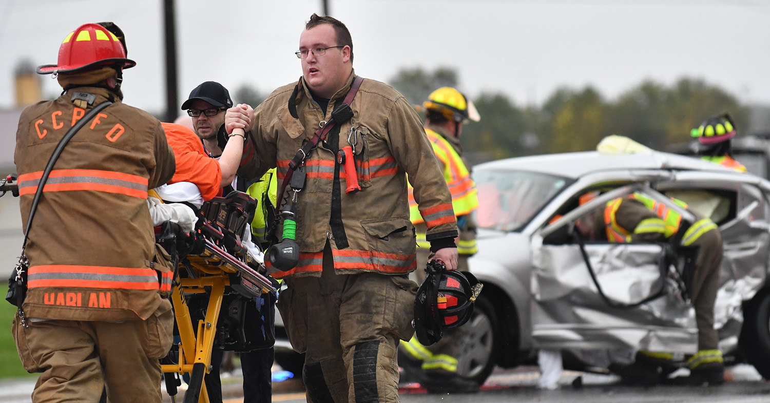 Lt. Austyn Wiesman, of the Carbon Cliff-Barstow Fire District, holds the hand of a driver involved in a three vehicle accident south of the intersection of Illinois 5 and Barstow Road Wednesday, Oct. 10, 2018, in Carbon Cliff, Ill.  (Todd Mizener - Dispatch/Argus)
