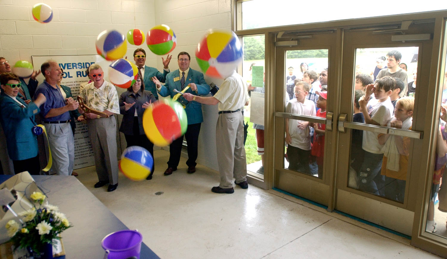 While local officials conduct a ribbon cutting inside, 75 wet and eager children wait in the rain for the opening of the new Riverside Aquatic Center in Moline, Illinois. The new center features zero-depth entry, lap lanes, a diving well, water play stations, sand playgrounds, a concession stand and new bathhouse. (Todd Mizener - Dispatch/Argus)